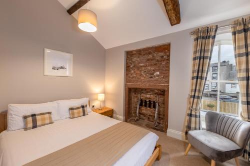 een slaapkamer met een bed en een stoel en een open haard bij Scotch Arms Mews Bed & Breakfast in Brampton