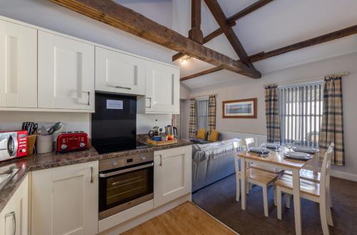 a kitchen with white cabinets and a table with chairs at Brampton Holiday Homes - The Mews Apartment in Brampton