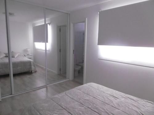 a white bedroom with a mirror and a bed at DEPTOS VIP en EDIFICIO FRENTE AL MAR-ZONA CONSTITUCION in Mar del Plata