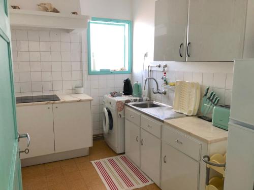 cocina blanca con fregadero y lavavajillas en Casa do Viajante - Family, en Zambujeira do Mar