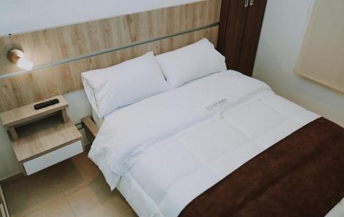 
a white bed with a white comforter and pillows at HOTEL GRAND BOUTIQUE in Fusagasuga
