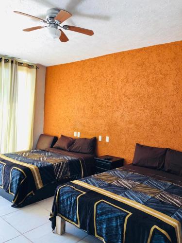 a bedroom with two beds and a ceiling fan at Bungalows La Perla Playa Azul in Playa Azul