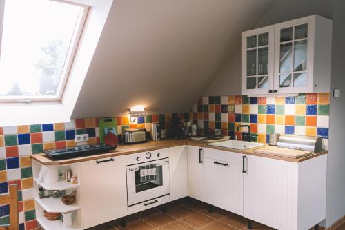 a small kitchen with white cabinets and colorful tiles at Pannónia Apartment in Göd