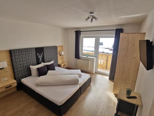 1 dormitorio con cama y ventana grande en Apart Bergglück, en Sankt Leonhard im Pitztal