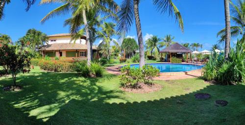 a resort with a swimming pool and palm trees at Grimms Pousada de Contos in Porto de Sauipe