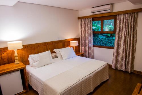 a bedroom with a white bed and a window at Pousada das Lavandas in Campos do Jordão