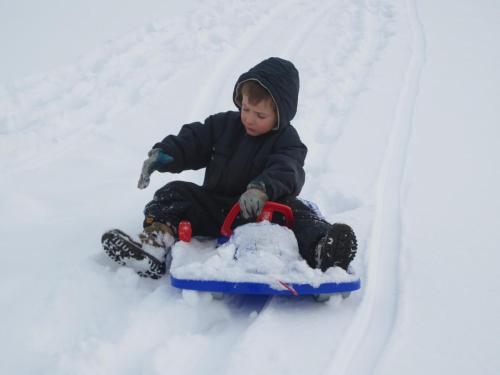 a young child riding a sled in the snow at Ferienhaus "Zur alten Schmiede" in Mariahof