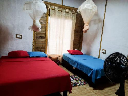 two beds in a room with red and blue at Tatacoa Star Eco Hotel in Villavieja