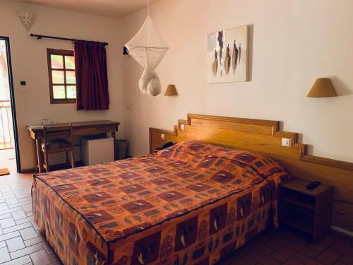 a bedroom with a bed and a desk in it at LES JARDINS DU FLAMBOYANT in Ziguinchor