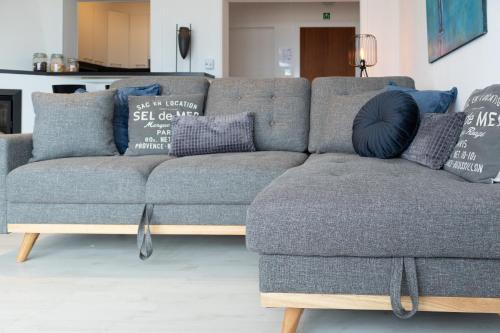 a blue couch with pillows on it in a living room at Modern appartement met uniek zeezicht in Koksijde