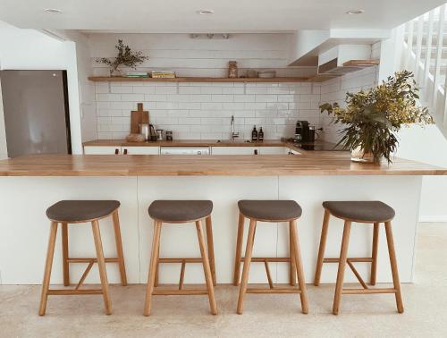 a kitchen with three bar stools at a counter at The Loft - beautiful central Barossa apartment in Tanunda