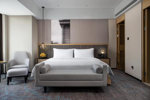 a bedroom with a large bed and a chair at Crowne Plaza Shanghai Fudan, an IHG Hotel in Shanghai