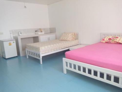 1 Schlafzimmer mit 2 Betten, einem Tisch und einem Kühlschrank in der Unterkunft Dmk Don Mueang airport Guest House meetgreet service in Thung Si Kan