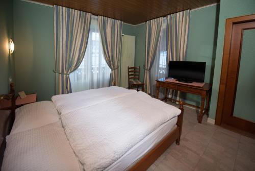 a bedroom with a bed and a desk with a computer at Hôtel - Restaurant Le Manoir in Vaulruz