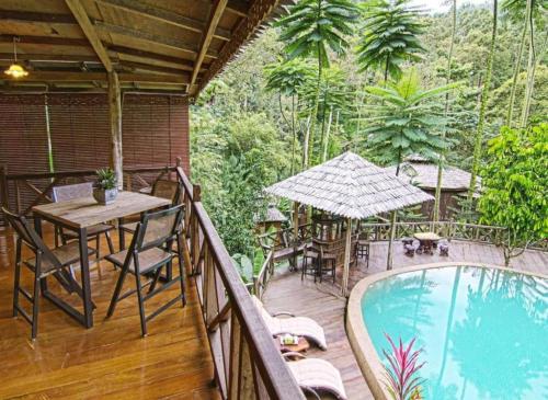 a balcony with a table and chairs and a swimming pool at Fig Tree Hills Resort (花果山度假村) in Bayan Lepas