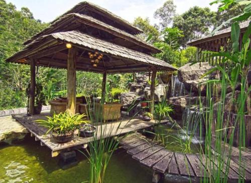 a wooden bridge over a pond with a gazebo at Fig Tree Hills Resort (花果山度假村) in Bayan Lepas