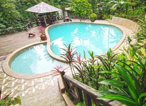 a swimming pool in a garden with a wooden deck at Fig Tree Hills Resort (花果山度假村) in Bayan Lepas