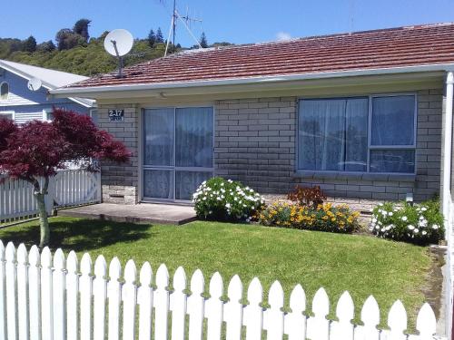 una cerca blanca frente a una casa con flores en Fantastic Two Bedroom Unit en Whakatane