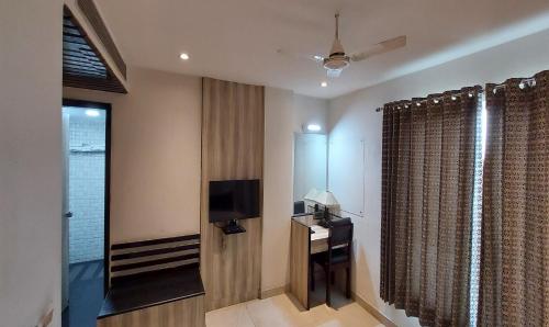 a hotel room with a television and a desk and curtains at Broadway Inn in Jaipur