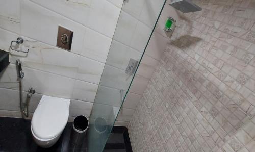 a bathroom with a toilet and a glass wall at Broadway Inn in Jaipur