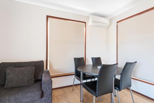 a dining room with a table and black chairs at Discovery Parks - Coogee Beach in Coogee