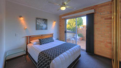 1 dormitorio con 1 cama y puerta que da a un patio en Cousins Motor Inn, en Inverell