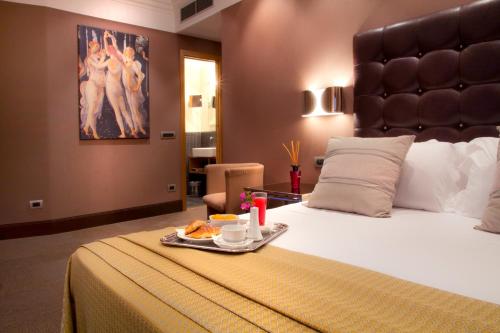 a hotel room with a bed with a tray of food on it at Marcella Royal Hotel - Rooftop Garden in Rome
