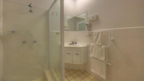 a bathroom with a shower and a sink and a mirror at Cousins Motor Inn in Inverell
