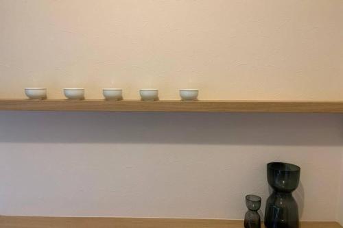 four bowls sitting on a shelf with a vase at Kyoto Osaka SUMIREYA in Takatuki