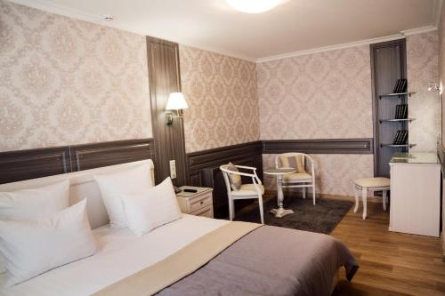 ウスリースクにあるHotel "Ussuriysk"のベッド、テーブル、椅子が備わるホテルルームです。