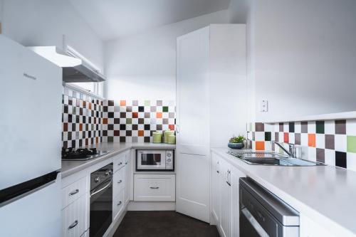 a white kitchen with a stove and a sink at Station Master's House in Castlemaine