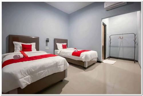 a bedroom with two beds with red and white sheets at RedDoorz Syariah near T2 Juanda Airport 2 in Dares