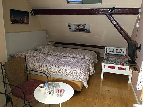 a small bedroom with two beds and a table at Paul en Lettie's Bed and Breakfast in Westbroek
