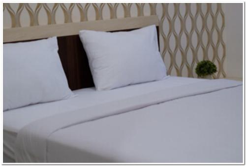 a bed with white sheets and pillows in a room at RedDoorz Syariah at Omah Sawah in Balong