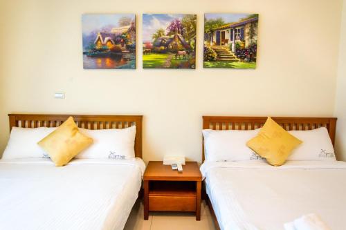 2 camas en una habitación con pinturas en la pared en Kenting Muchen INN, en Hengchun