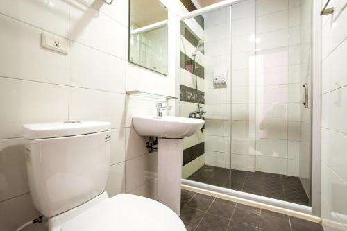 La salle de bains est pourvue de toilettes, d'un lavabo et d'une douche. dans l'établissement Kenting Muchen INN, à Hengchun Old Town