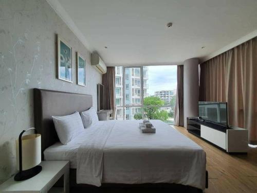 a bedroom with a large white bed and a television at My Resort Huahin by Vas in Hua Hin