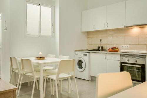 a white kitchen with a white table and chairs at 1a Van Halen in Vecindario
