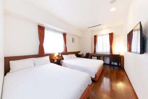 a hotel room with two beds and two lamps at The OneFive Osaka Midosuji in Osaka