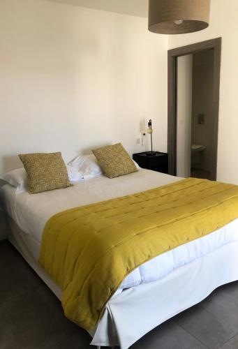 une chambre avec un grand lit avec une couverture jaune dans l'établissement Appartement 2 chambres Monte Stella, à Monticello
