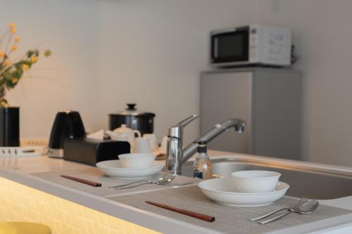 a kitchen counter with three bowls and a sink at 谷町君ホテル WE 難波28 in Osaka