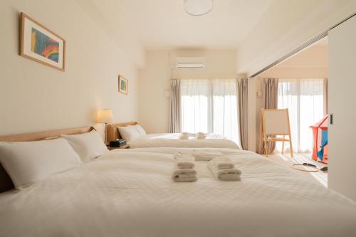 a bedroom with two beds with towels on the bed at 谷町君ホテル WE 難波28 in Osaka