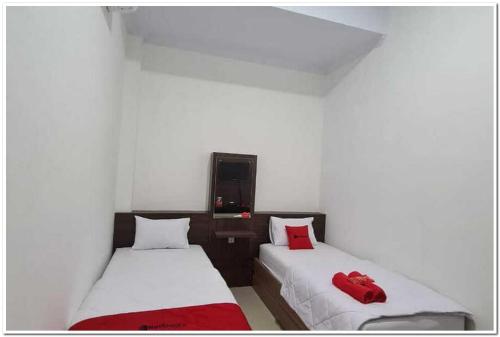 2 camas en una habitación con almohadas rojas. en RedDoorz near Moro Mall Purwokerto 2, en Purwokerto