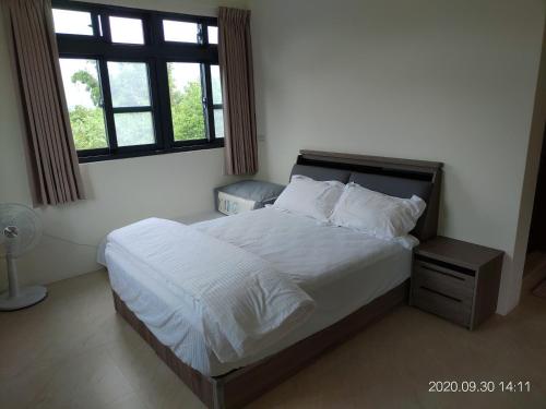 a bedroom with a large bed with white sheets and a window at 青禾軒 in Fuli