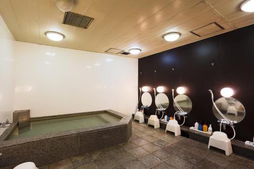 a bathroom with a tub and sinks and mirrors at Capsule Land Yushima (Male Only) in Tokyo