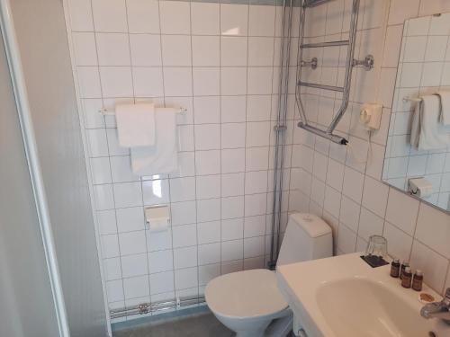 a white bathroom with a toilet and a sink at Hotel Statt Söderhamn by First Hotels in Söderhamn