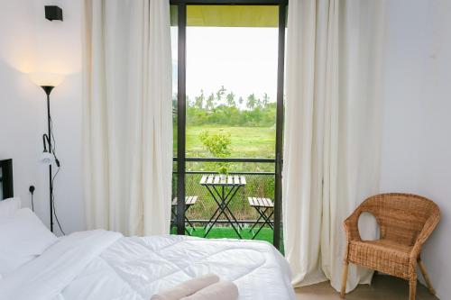 a bedroom with a bed and a view of a balcony at Langkawi Green View Cottage in Pantai Cenang