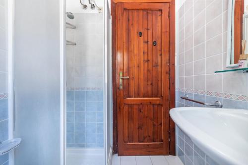 Łazienka z drewnianymi drzwiami, wanną i umywalką w obiekcie Villa Mercede w mieście Muravera