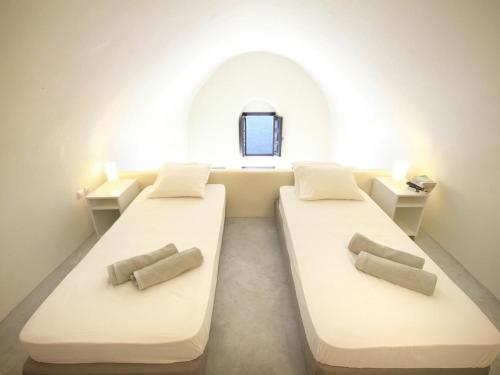two beds in a room with a window at Alafouzou Cave Loft by SV in Oia