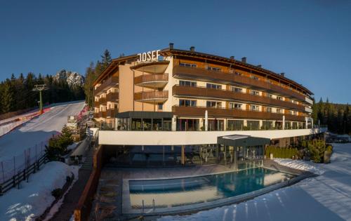 a hotel with a swimming pool in front of a building at Josef Mountain Resort in Avelengo